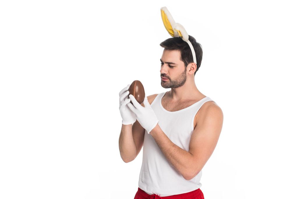 Muž s uši zajíček drží čokoládové vejce izolované na bílém, Velikonoční koncepce - Fotografie, Obrázek