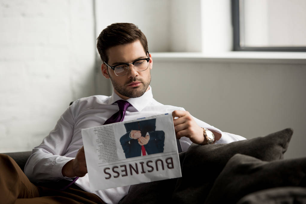 Empresário sentado no sofá e lendo jornal
  - Foto, Imagem