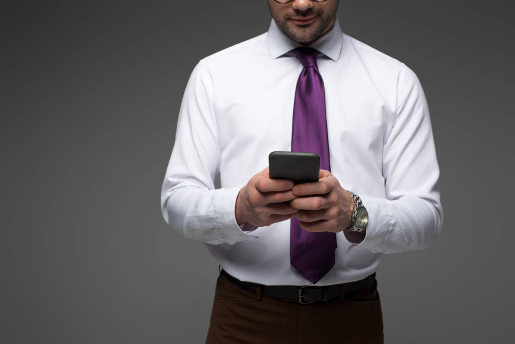 Vue recadrée d'un homme d'affaires tenant un smartphone dans des mains isolées sur gris
 - Photo, image
