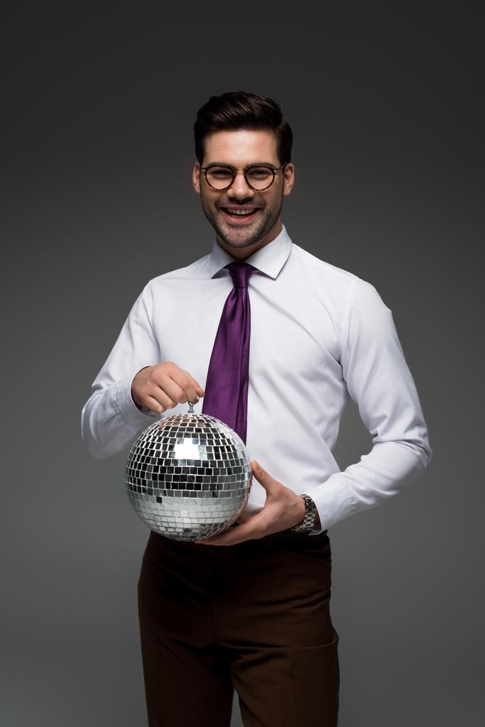 Smiling businessman holding glass disco ball isolated on grey - Photo, Image
