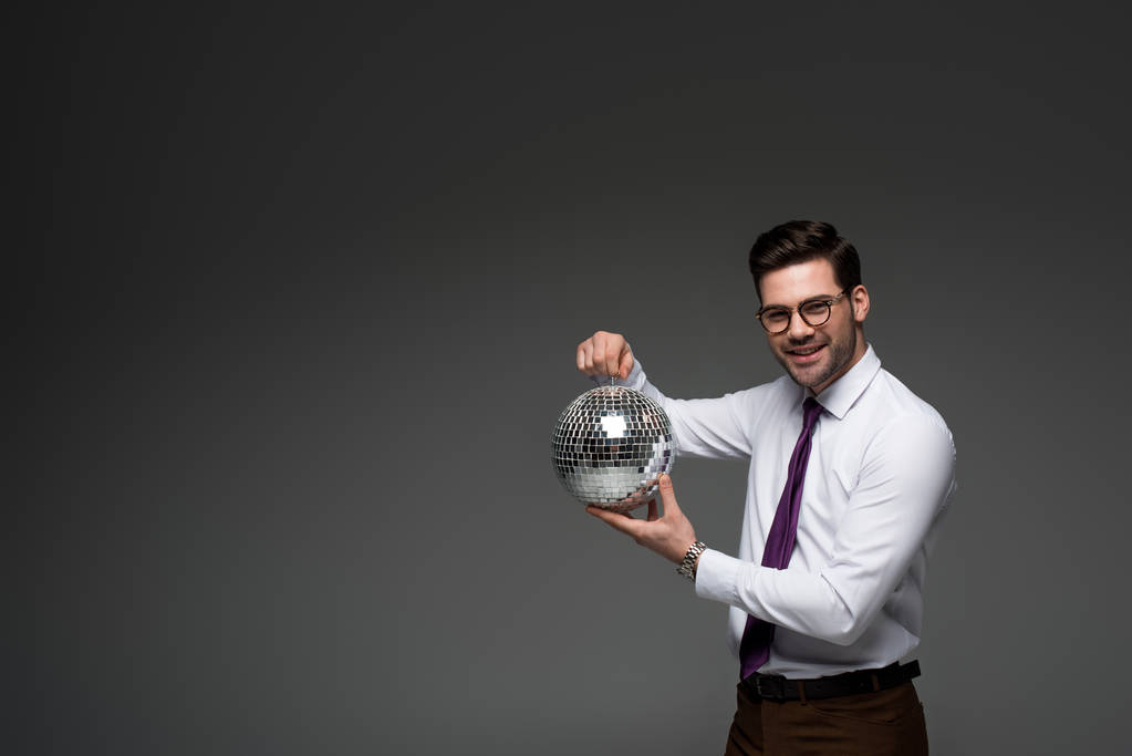 elegante hombre de negocios mostrando bola disco de vidrio aislado en gris
 - Foto, Imagen