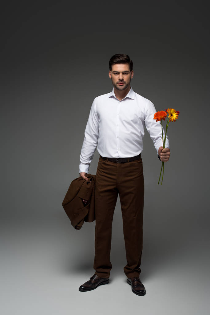 Vista di uomo d'affari elegante che tiene il mazzo di fiori su grigio
 - Foto, immagini