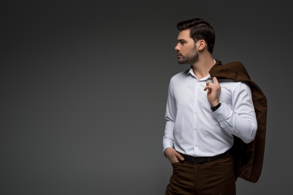 Side view of young businessman with jacket on shoulder isolated on grey - Photo, Image