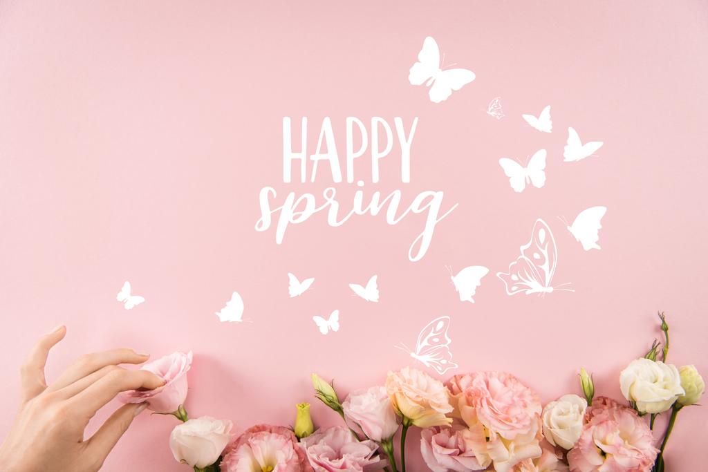 Top view of hand arranging beautiful tender flowers with HAPPY SPRING sign and butterflies isolated on pink background - Photo, Image