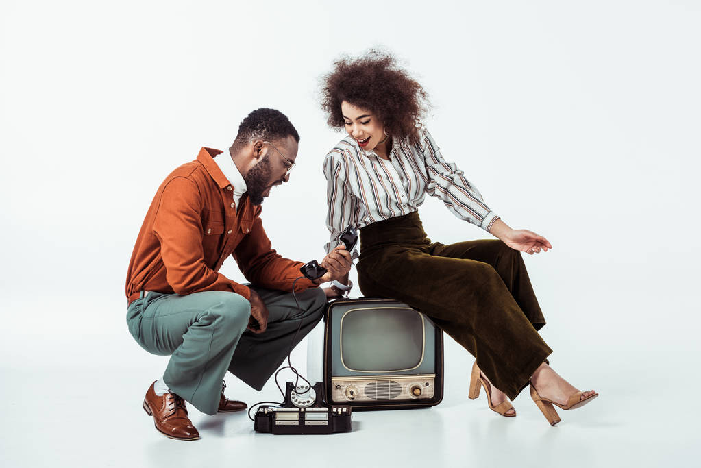 african american retro styled couple looking with surprise at vintage phone on white - Photo, Image
