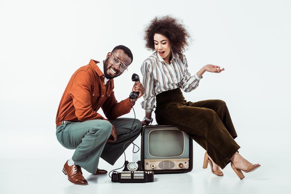 Gelukkig Afro-Amerikaanse retro stijl paar met vintage televisie en telefoon op wit - Foto, afbeelding