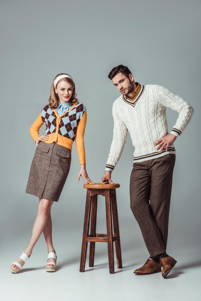 beau couple de style rétro posant avec chaise en bois sur gris
 - Photo, image