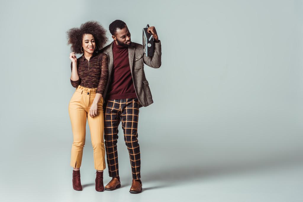 felice coppia afro-americana in stile retrò con radio vintage su grigio
 - Foto, immagini