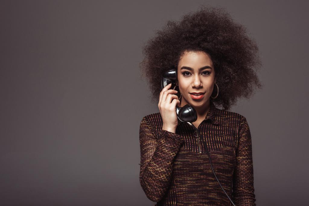 Afrikkalainen amerikkalainen retro tyylistä tyttö puhuu vintage paikallaan puhelin eristetty harmaa
 - Valokuva, kuva