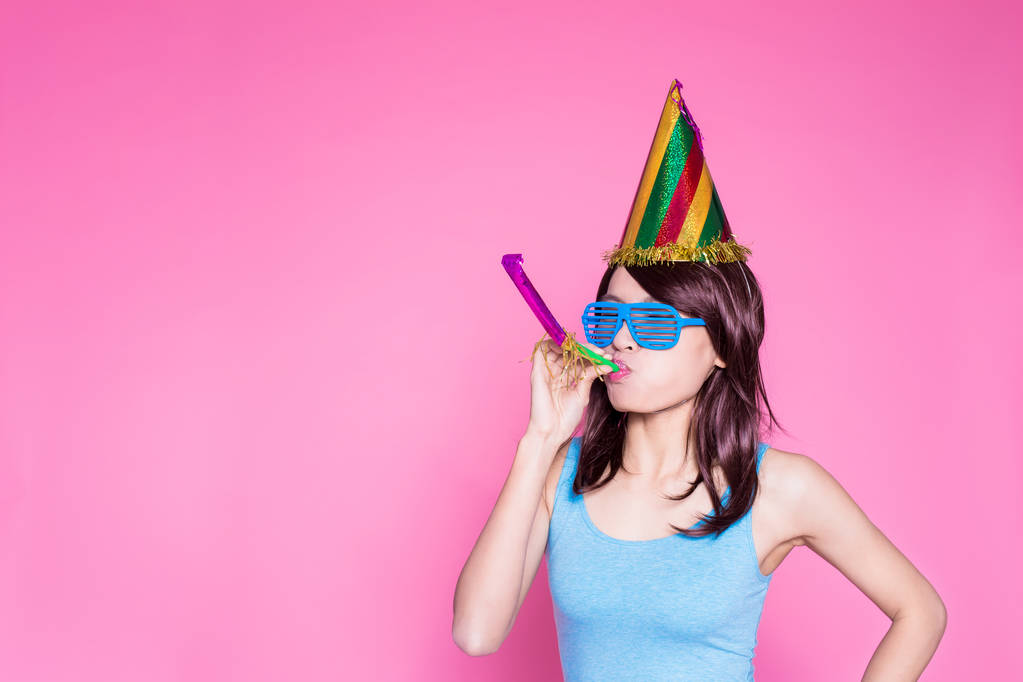 giovane donna che indossa un cappello da festa con rumorista sullo sfondo rosa
 - Foto, immagini