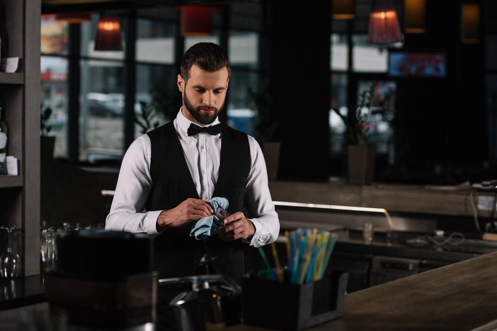 bonito barman limpeza de vidro com pano à noite
 - Foto, Imagem