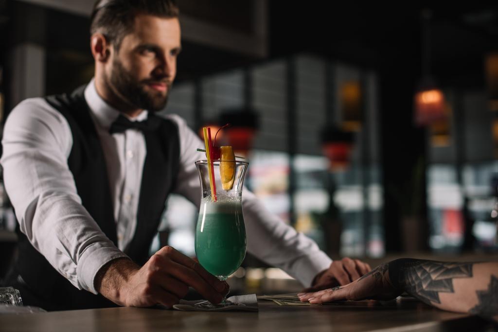 όμορφος μπάρμαν δίνοντας αλκοολούχο ποτό κορίτσι στο μπαρ μετρητή - Φωτογραφία, εικόνα