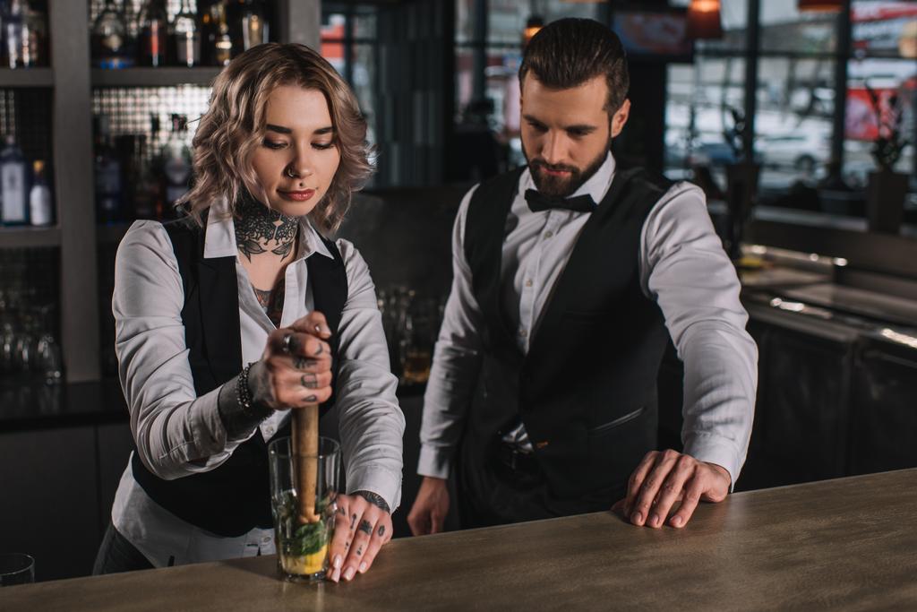 θηλυκό μπάρμαν δείχνει συνάδελφό του πώς να προετοιμάσει το ποτό σας στο μπαρ - Φωτογραφία, εικόνα