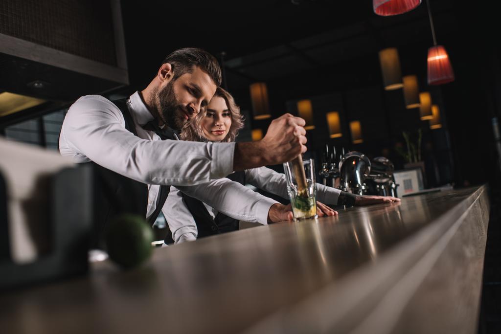 male bartender showing colleague how to prepare drink at bar - Photo, Image