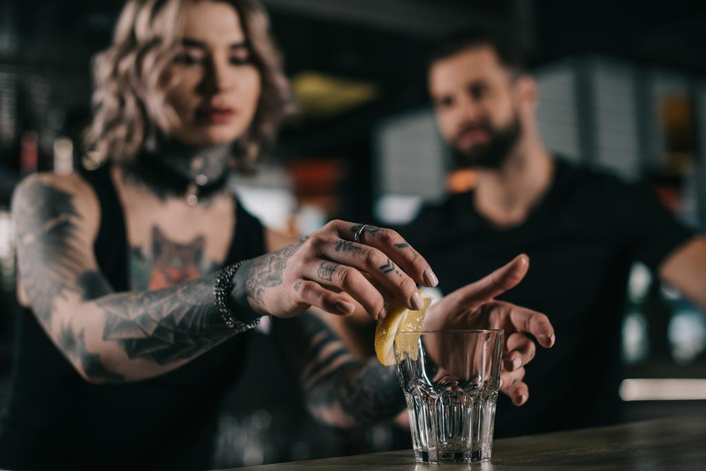 μπάρμαν βάζοντας κομμάτι του λεμονιού σε ποτήρι στο μπαρ - Φωτογραφία, εικόνα