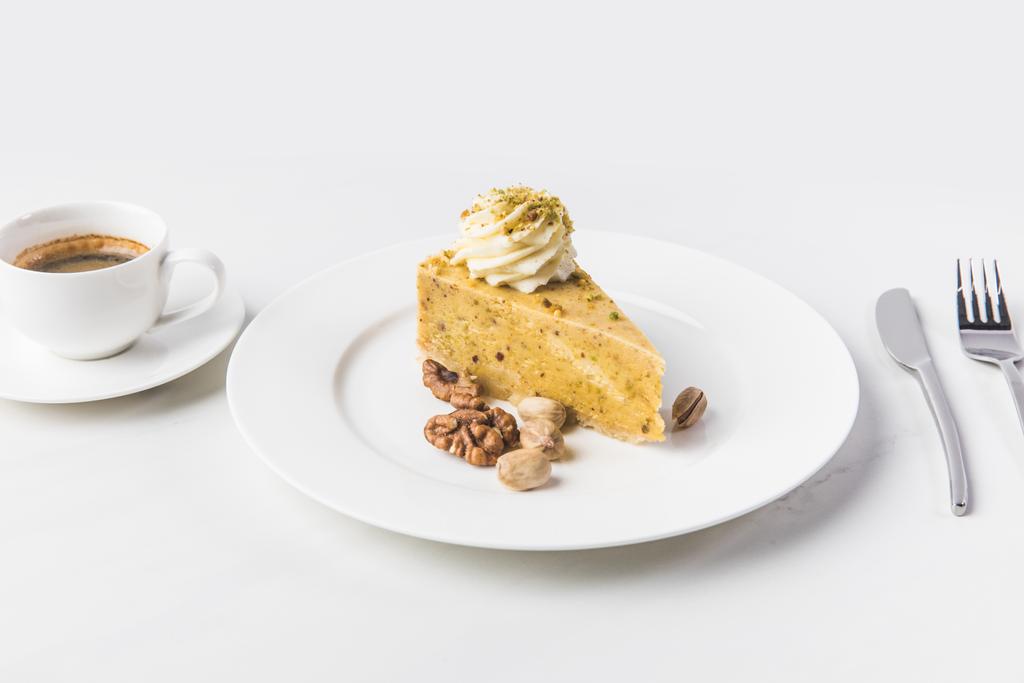 Nahaufnahme des Kuchenstücks mit Nüssen und Tasse Kaffee isoliert auf weißer Oberfläche - Foto, Bild