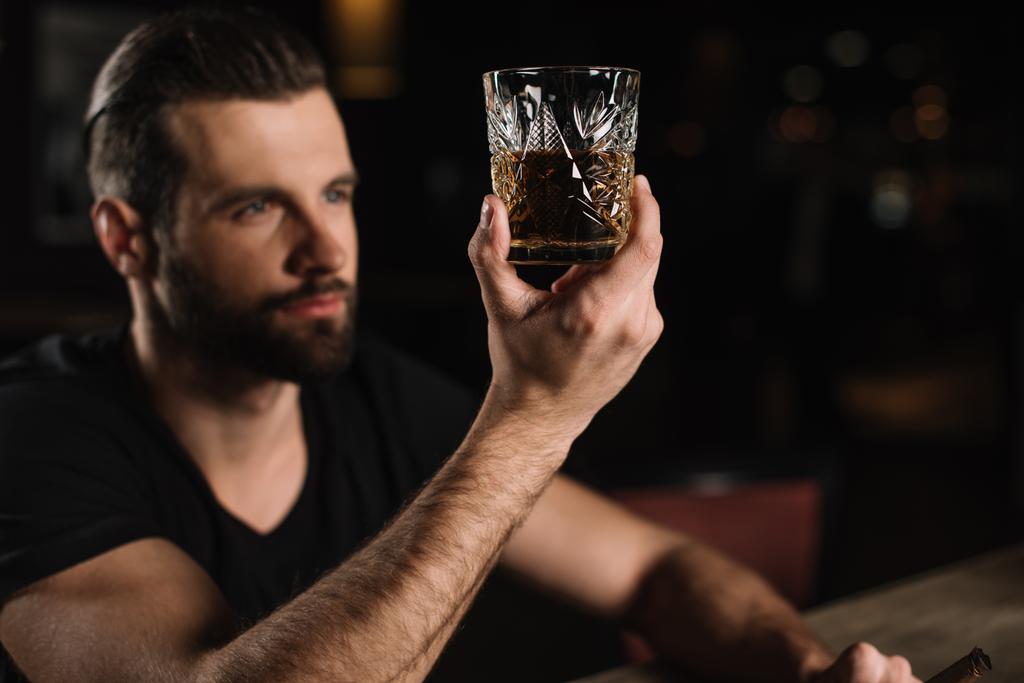 hombre sentado en el mostrador del bar y mirando un vaso de whisky en el bar
 - Foto, imagen