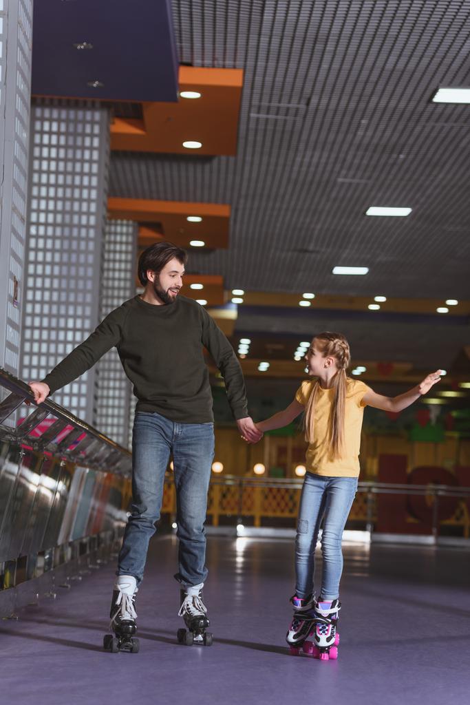 父と娘が一緒にローラー スケート場でスケートをしながら手を繋いで - 写真・画像