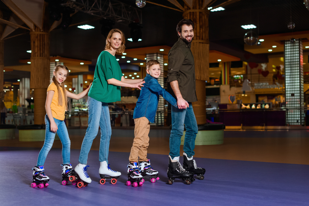 親と子供一緒にローラー スケート場でスケート - 写真・画像