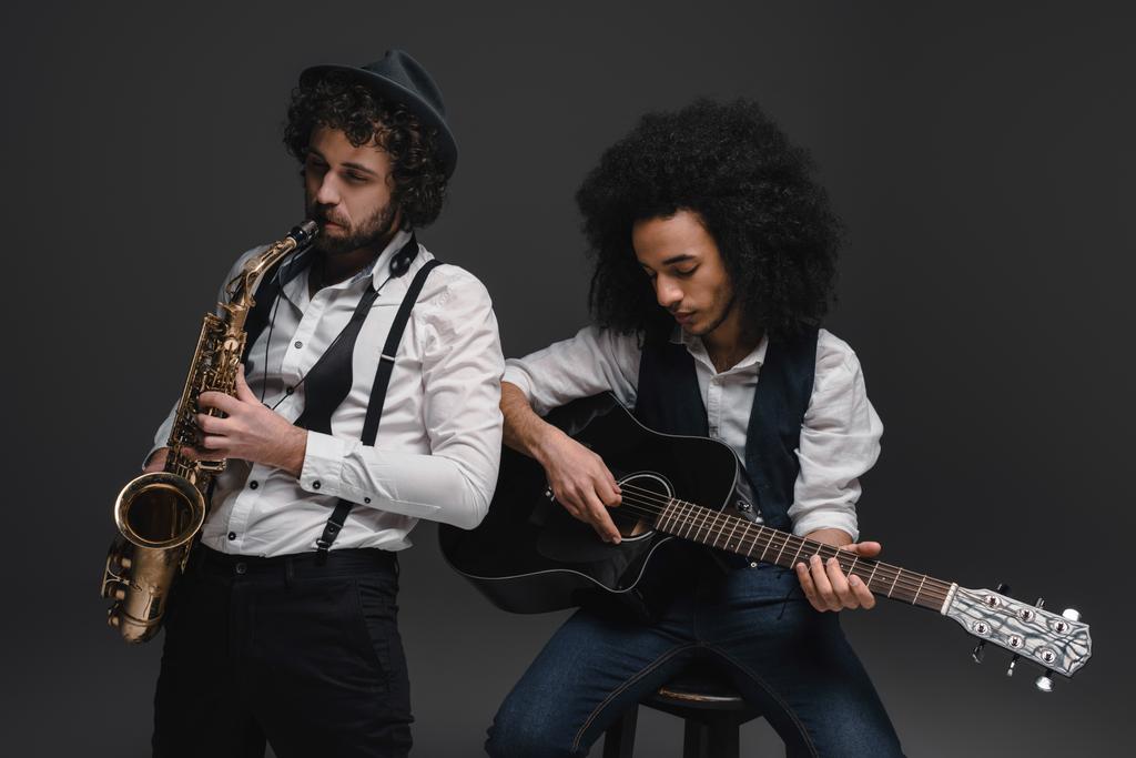 dueto de músicos tocando sax e guitarra acústica no preto
 - Foto, Imagem