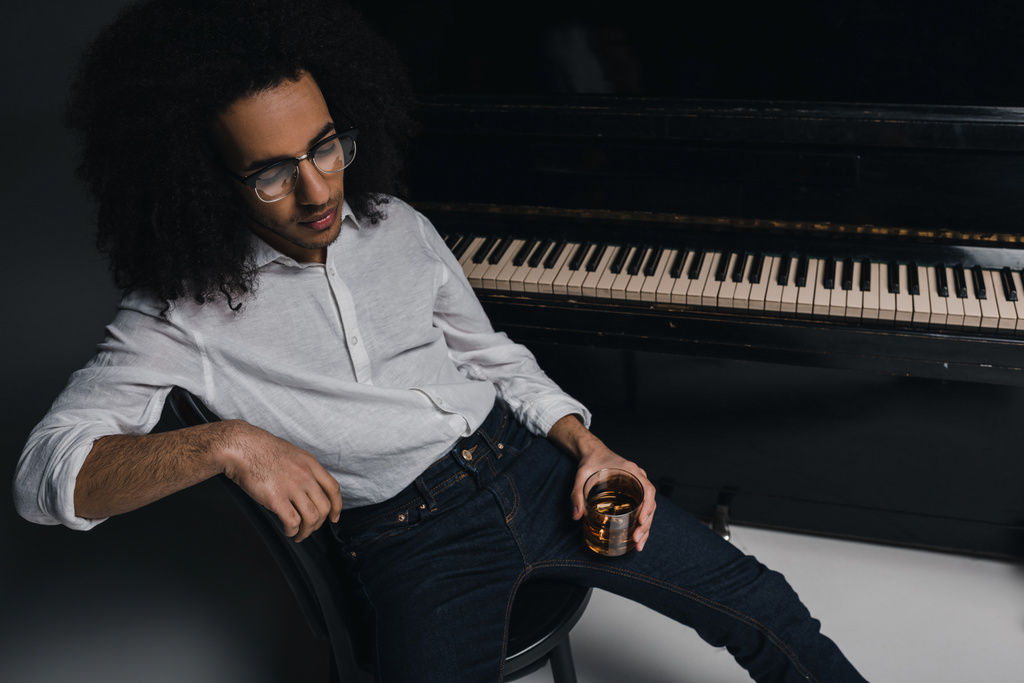 Африканский американский музыкант со стаканом виски перед фортепиано
 - Фото, изображение