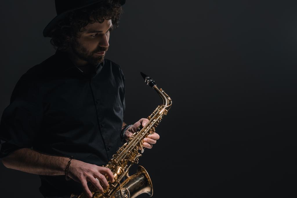 jovem músico tocando saxofone no preto
 - Foto, Imagem