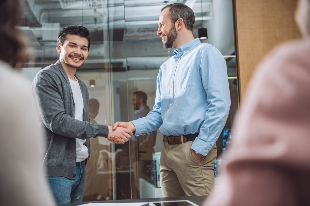 smiling business colleagues shaking hands at modern office - Photo, Image