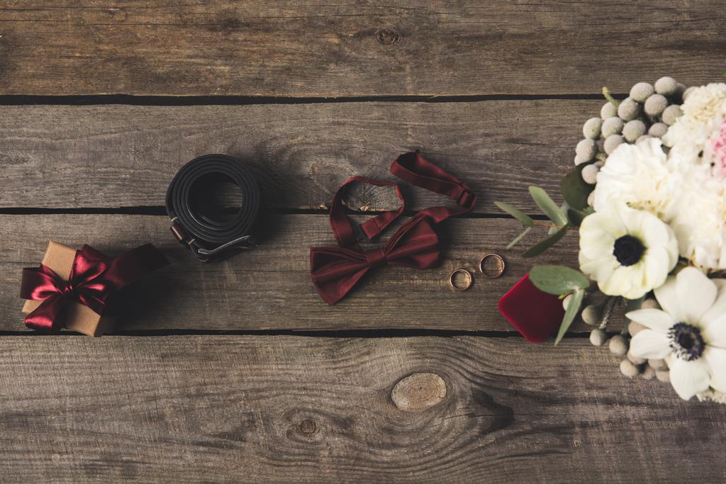 flache Liege mit Trauringen, Schmuckschatulle, Brautstrauß, Geschenk- und Bräutigam-Accessoires auf Holztischplatte - Foto, Bild