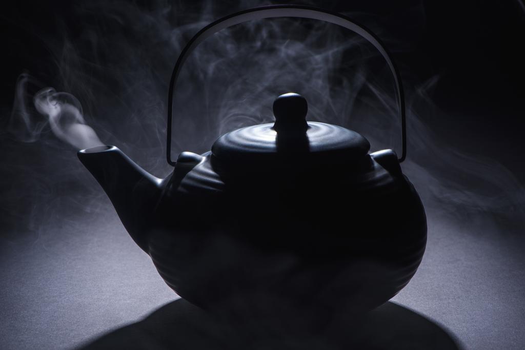 close-up view of black chinese teapot with hot steam on black  - Photo, Image