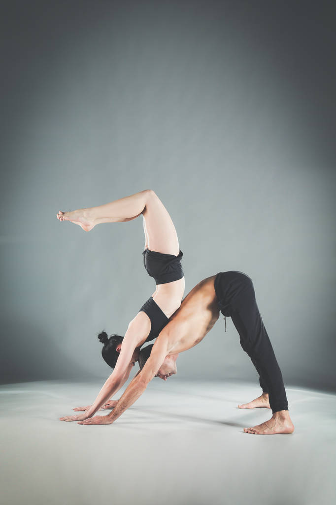 Молода пара практикує акро-йогу на килимку в студії разом. Акройога. Пара йога. партнерська йога
. - Фото, зображення