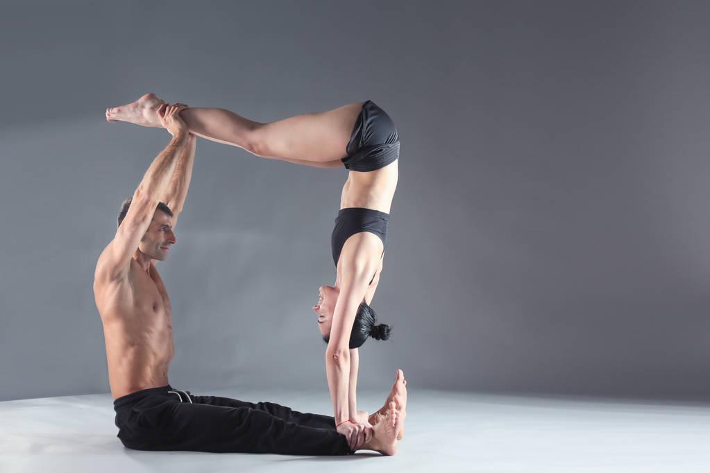 Νεαρό ζευγάρι εξάσκηση acro yoga σε χαλί στο στούντιο μαζί. Acroyoga. Γιόγκα ζευγάρι. Εταίρους γιόγκα. - Φωτογραφία, εικόνα