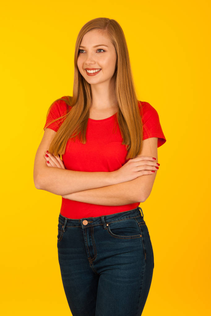 Красива молода жінка в червоній сорочці і джинсах над жовтим фоном
 - Фото, зображення