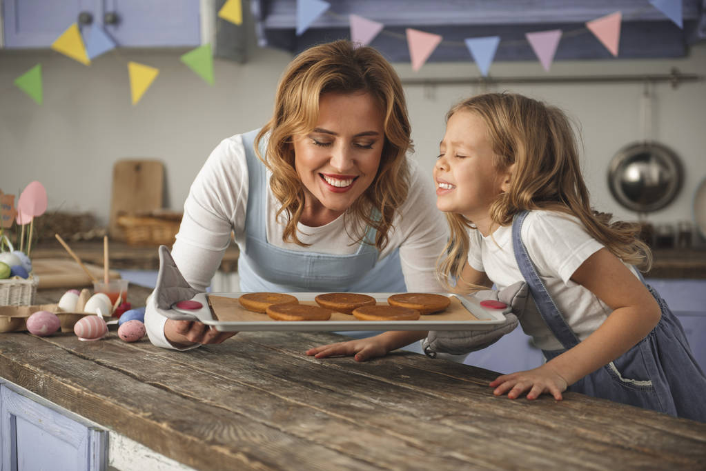 Cheerful mother and kid sniffing pastry on the tray - Photo, Image