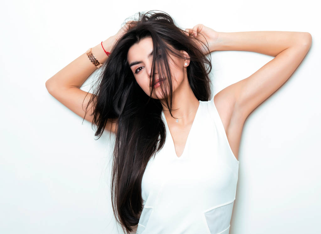 hermosa joven con el pelo largo y negro vestido y posando sobre fondo blanco
 - Foto, Imagen
