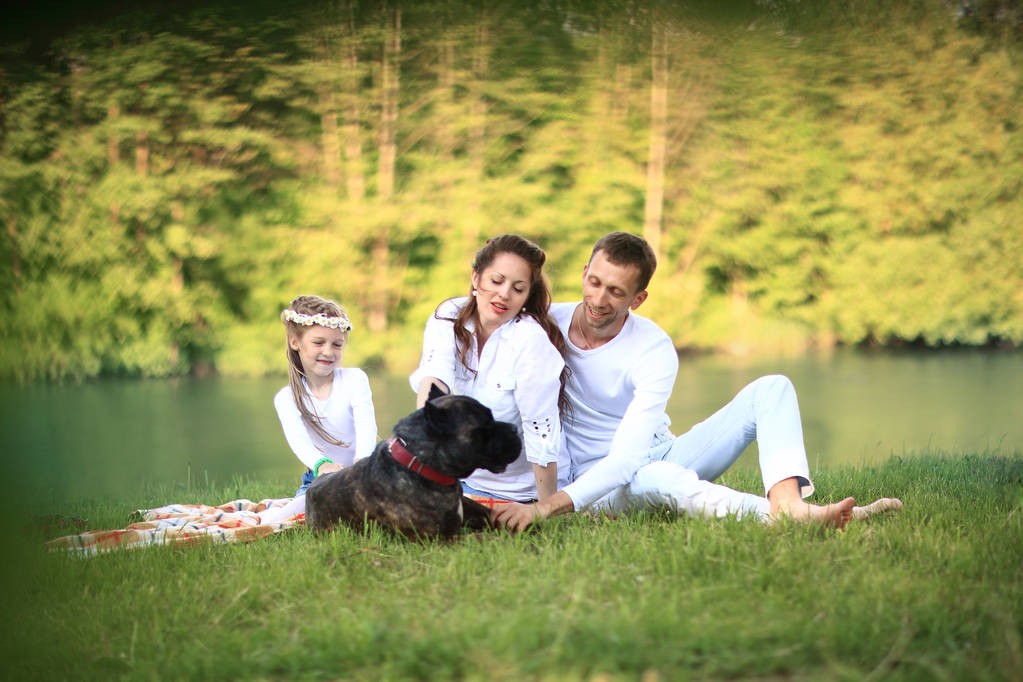 Güneşli bir yaz gününde piknikte köpekli mutlu bir aile. pregn - Fotoğraf, Görsel