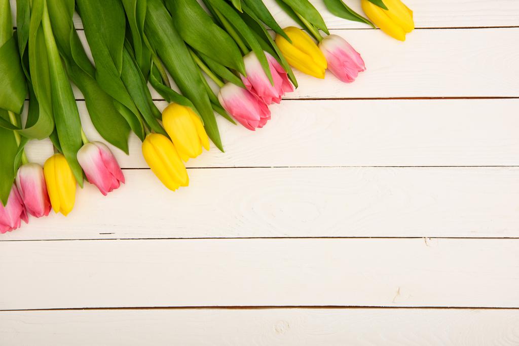 vista superior de hermosos tulipanes rosados y amarillos en la superficie de madera
 - Foto, Imagen