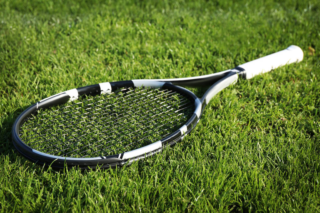 Raqueta de tenis moderna sobre hierba verde
 - Foto, Imagen