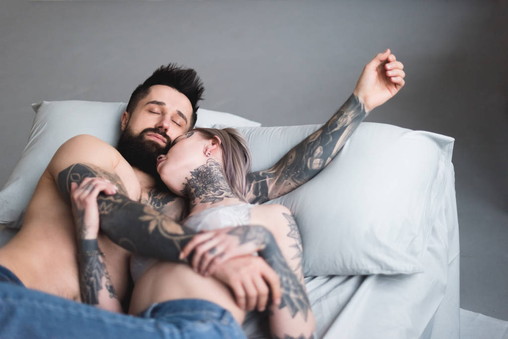 татуйована без сорочки пара спить на ліжку
 - Фото, зображення