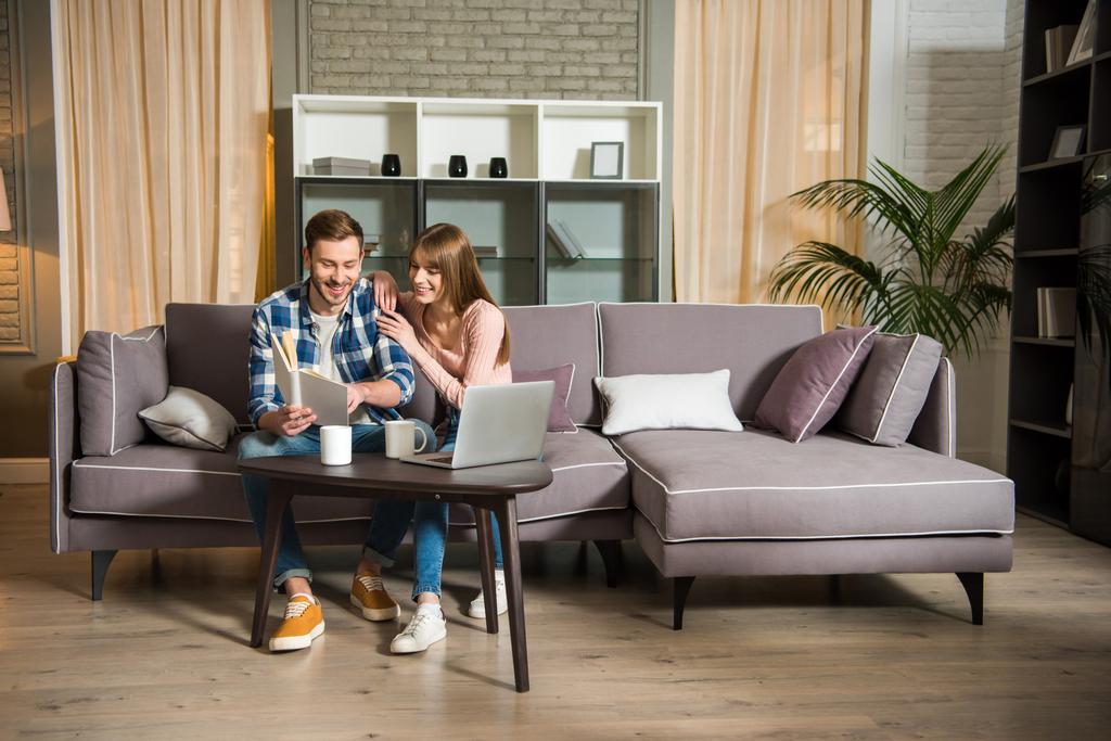 Giovane coppia seduta sul divano e lettura libro in soggiorno
 - Foto, immagini