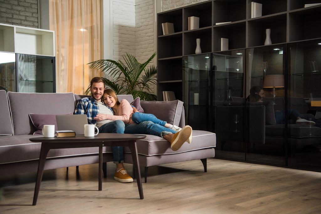 Casal se divertindo enquanto assiste laptop na sala de estar moderna
 - Foto, Imagem