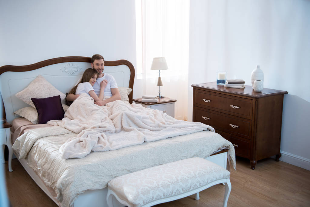 junge Frau liegt im modern eingerichteten Schlafzimmer auf der Brust ihres Freundes - Foto, Bild