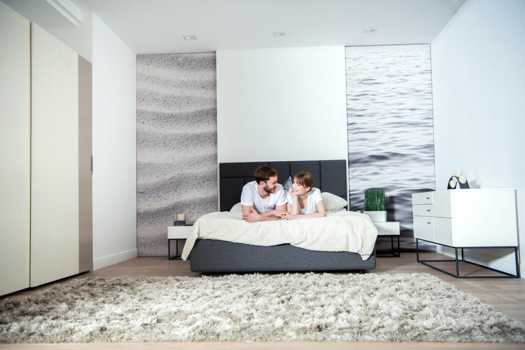 Młoda para leżącego w sypialni z nowoczesnym wnętrzem - Zdjęcie, obraz