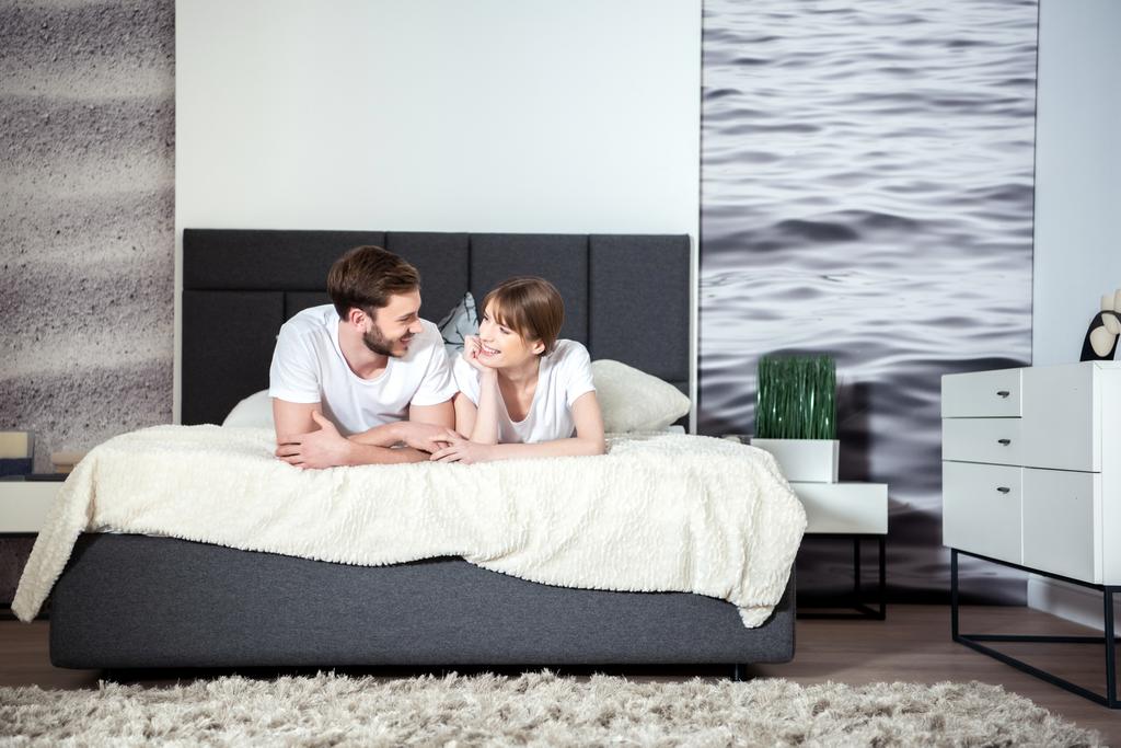 Счастливая пара лежала и разговаривала в уютной современной спальне
 - Фото, изображение