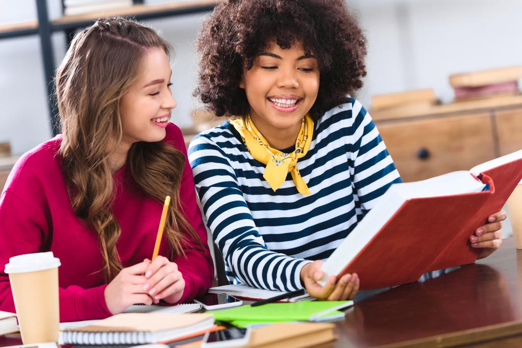 портрет молодих усміхнених мультикультурних студентів, які роблять домашнє завдання разом
 - Фото, зображення