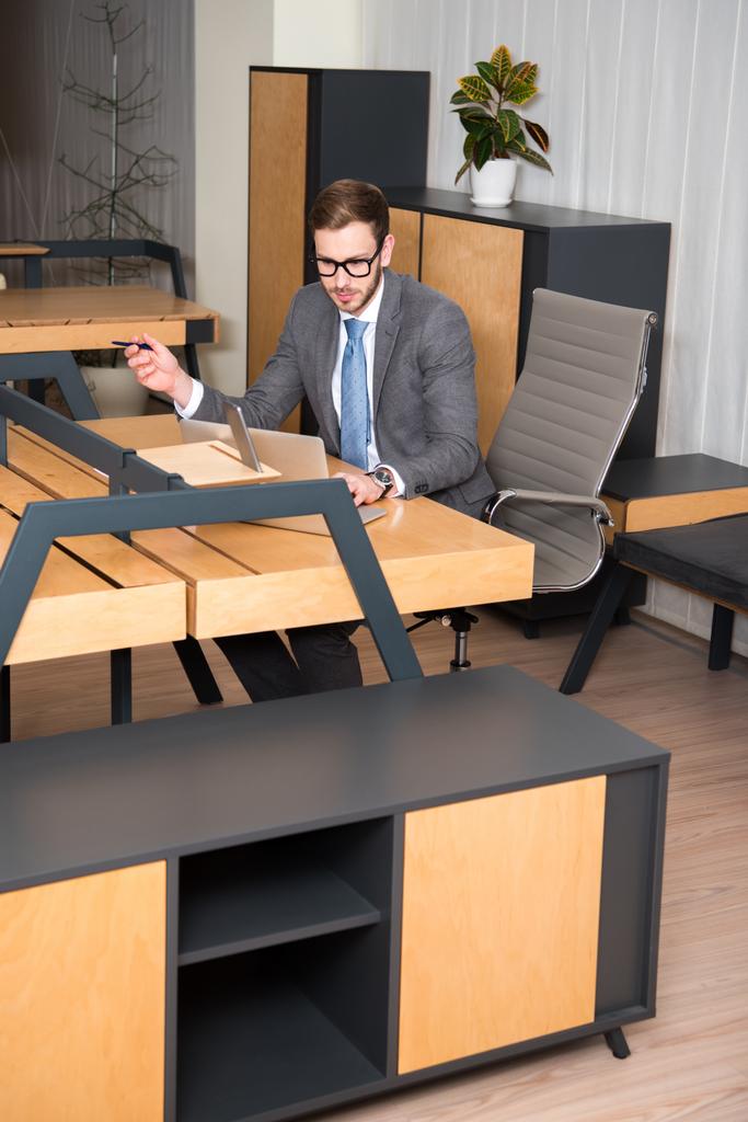 Giovane uomo d'affari che lavora a tavola con laptop in ufficio
 - Foto, immagini