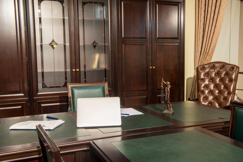 Innenraum des Büroraums mit Laptop, Statuette und Papieren auf dem Tisch  - Foto, Bild