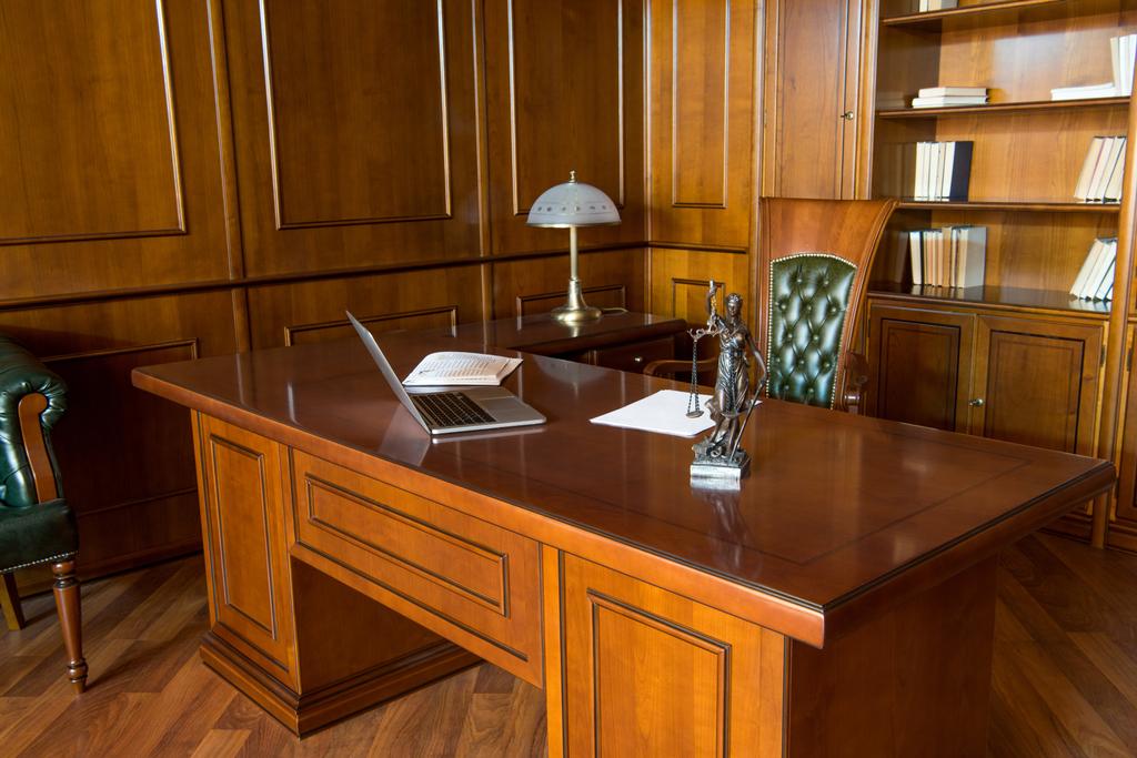 Interior de la sala de oficina con ordenador portátil, estatuilla y papeles en la mesa de madera
  - Foto, Imagen
