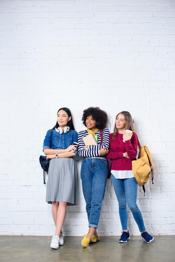 young multiracial students standing against white brick wall - Photo, Image
