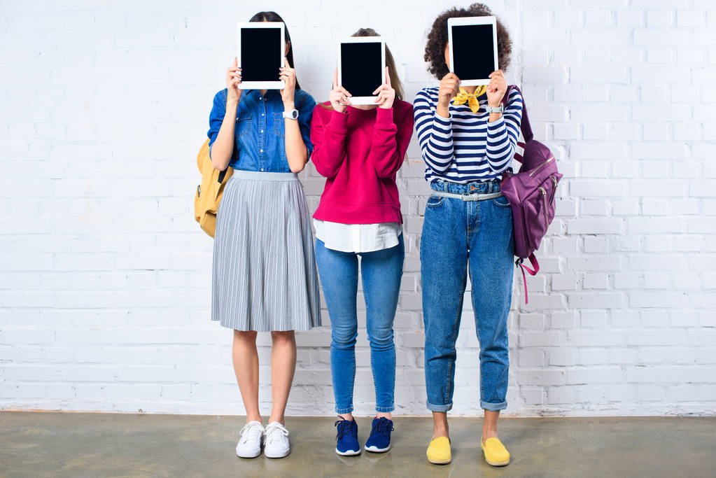 visão obscurecida de estudantes mostrando tablets com telas em branco nas mãos contra a parede de tijolo branco
 - Foto, Imagem