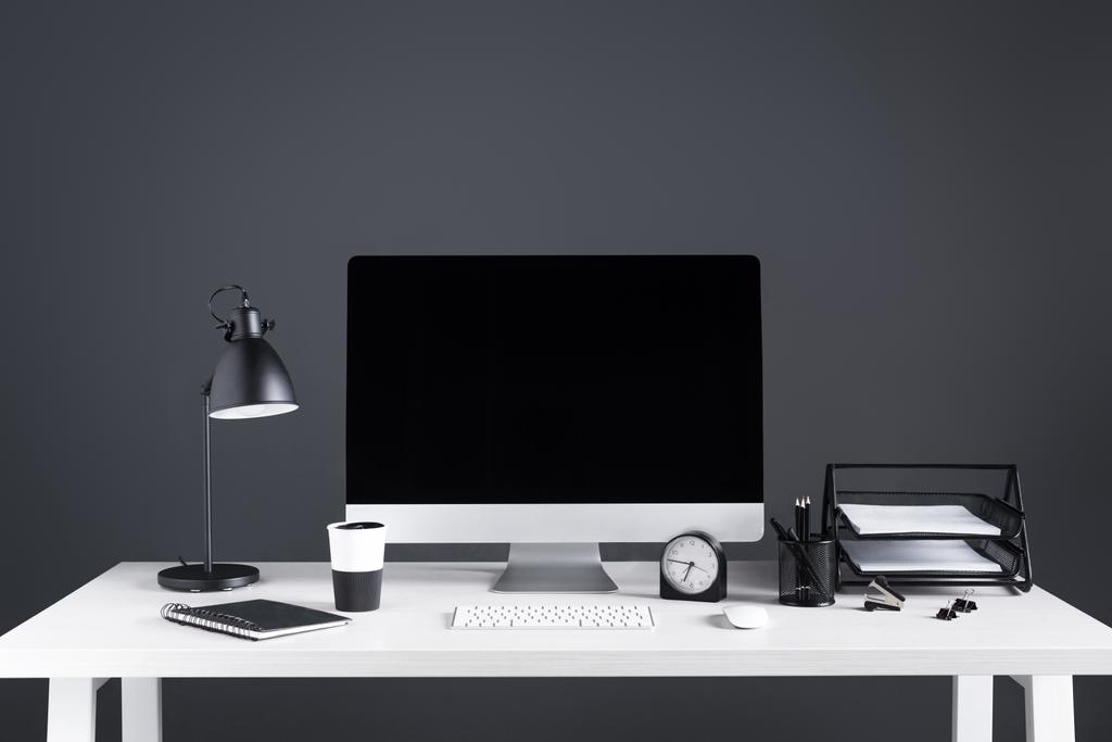 настільний комп'ютер з порожнім екраном, годинником та приладдям для офісу на робочому місці
  - Фото, зображення